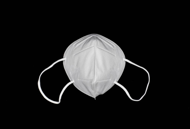 Μάσκα KN-95 μίας χρήσης ή νέα άσπρη ιατρική μάσκα. Πρόληψη COVID-19. H1N1, H5N1 μέτρα ασφαλείας. Απομονωμένα σε μαύρο φόντο. - Φωτογραφία, εικόνα