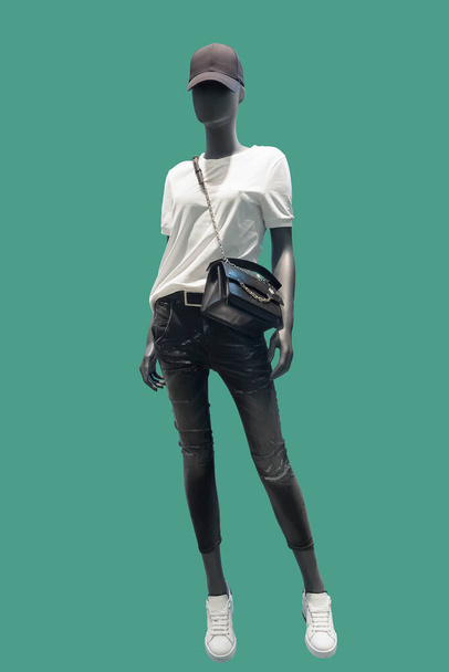 Image pleine longueur d'un mannequin femme portant un t-shirt blanc et un jean noir déchiré isolé sur un fond vert. - Photo, image