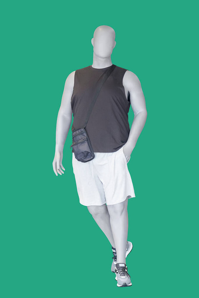 Imagem de comprimento total de um manequim de exibição masculino vestindo roupas de atletismo esportivo isolado em um fundo verde. - Foto, Imagem