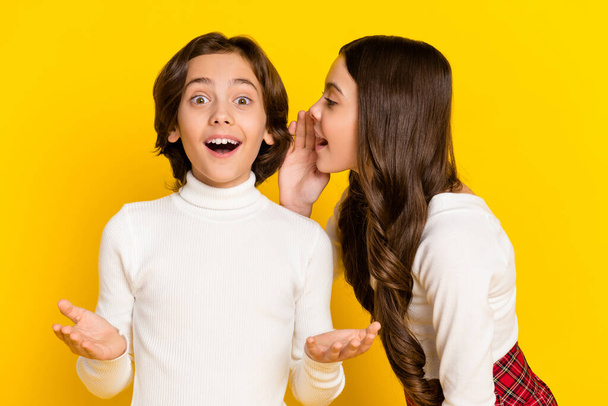 Photo portrait of small schollgirl tekking secret her friend isolated on vibrant yellow color background - Foto, Imagen