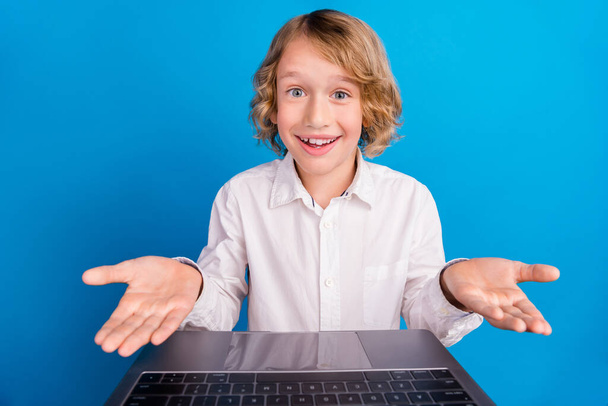 Портрет красивого модного веселого мальчика, посещающего занятия видео контакт вызова изолирован на ярко-голубом фоне - Фото, изображение