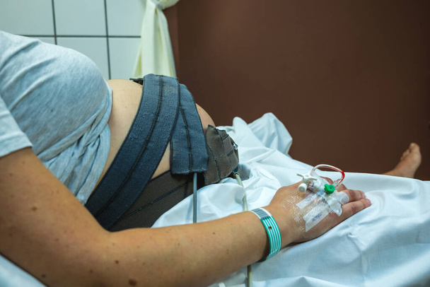 Zwangere vrouw opgenomen in het ziekenhuis met intraveneuze behandeling. - Foto, afbeelding