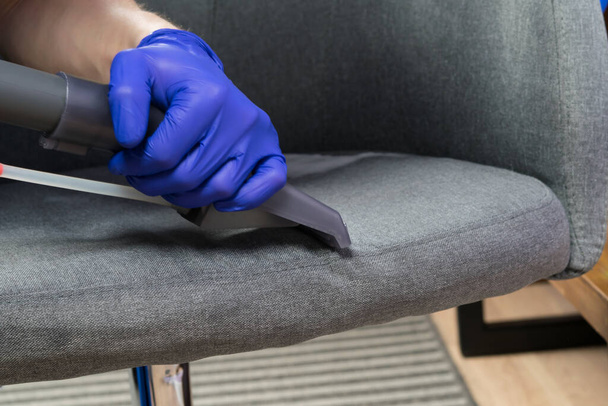 wet cleaning of the chair with a cleaning vacuum cleaner, hand in protective gloves, close-up - Foto, imagen