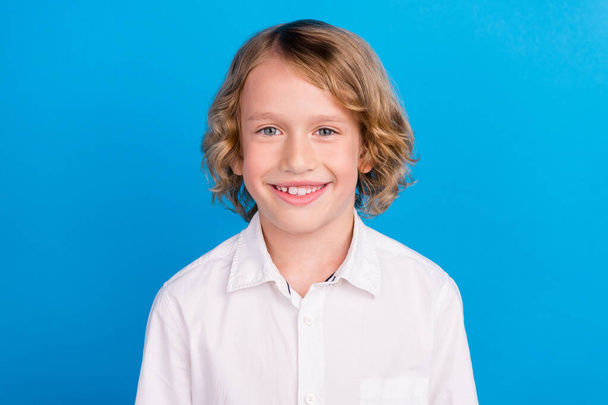 Портрет привлекательного содержания веселый мальчик в белой рубашке изолированы на ярком синем фоне цвета - Фото, изображение