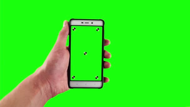 Ο άνθρωπος κατέχει ντεμοντέ smartphone με δείκτες εντοπισμού στην οθόνη έναντι πράσινο φόντο οθόνη - Πλάνα, βίντεο
