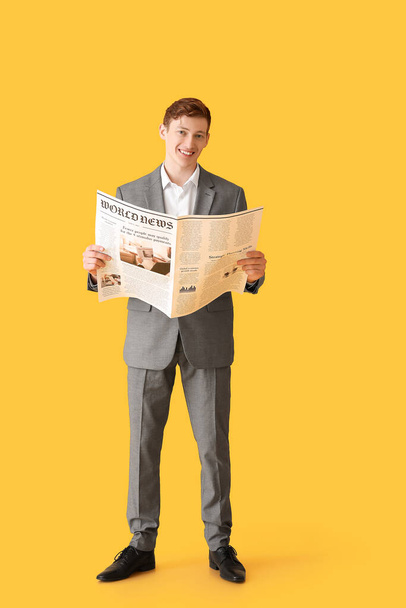 Young businessman reading newspaper on color background - Фото, изображение