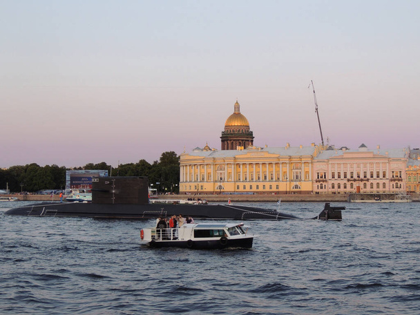 A black submarine and a motor boat on the Neva River in St. Petersburg, the Empire-style Admiralty building and the dome of St. Isaac's Cathedral in the background              - Photo, image