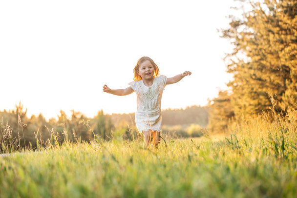 happy baby smiling. little girl running at sunset outdoor - Фото, изображение