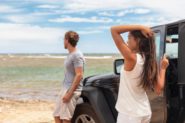 Couple on a road trip travel holiday in Hawaii driving car on beach. Young people tourists enjoying vacation - Fotografie, Obrázek