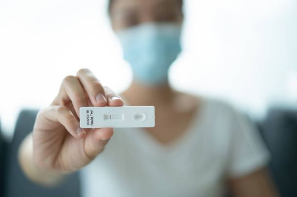 Asian young woman with hygiene protective face mask using SARS 2019-nCoV COVID-19 coronavirus antigen rapid test kit - ag test kit at home. COVID-19 antigen rapid test. - 写真・画像
