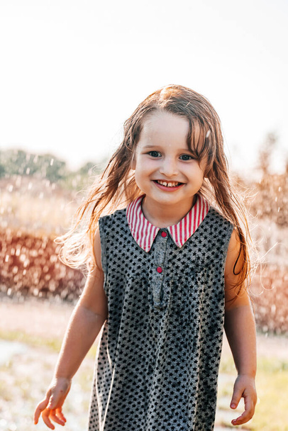 Счастливый ребенок улыбается. маленькая девочка бежит на закате на открытом воздухе - Фото, изображение