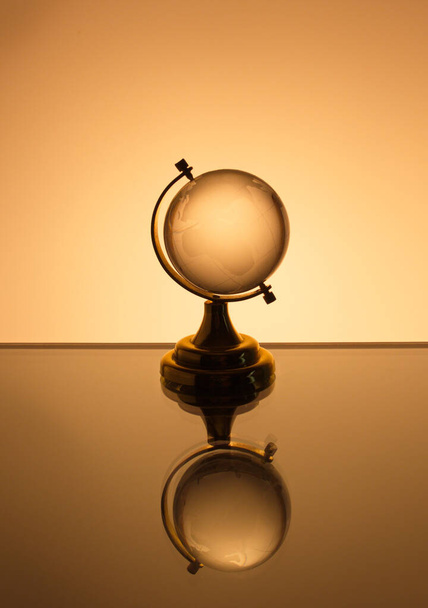 Small glass globe stands on a  brown  background - Zdjęcie, obraz