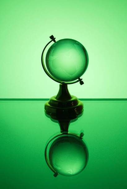 Small glass globe stands on a green background - Valokuva, kuva