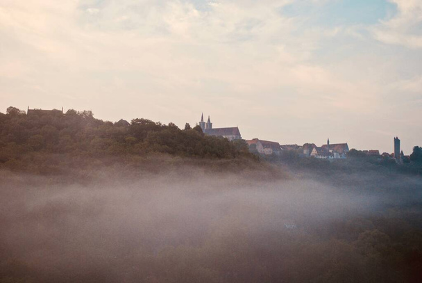 Rothenburg ob der Tauber w Bawarii, Niemcy: Miejska panorama jest zarysowana na wzgórzu nad zamgloną doliną. Zdjęcie lotnicze zrobione o świcie.  - Zdjęcie, obraz