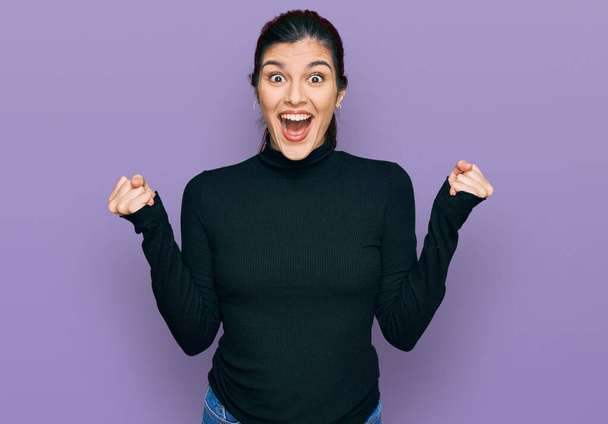 Young hispanic woman wearing casual clothes celebrating surprised and amazed for success with arms raised and open eyes. winner concept.  - Foto, Bild