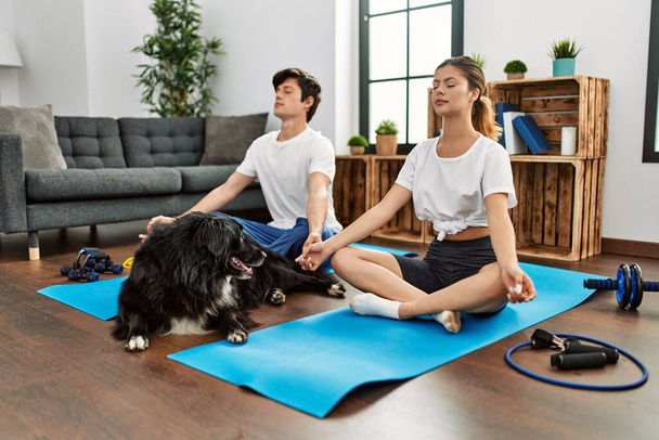 Молода біла пара концентрує тренування йоги з собакою вдома
. - Фото, зображення