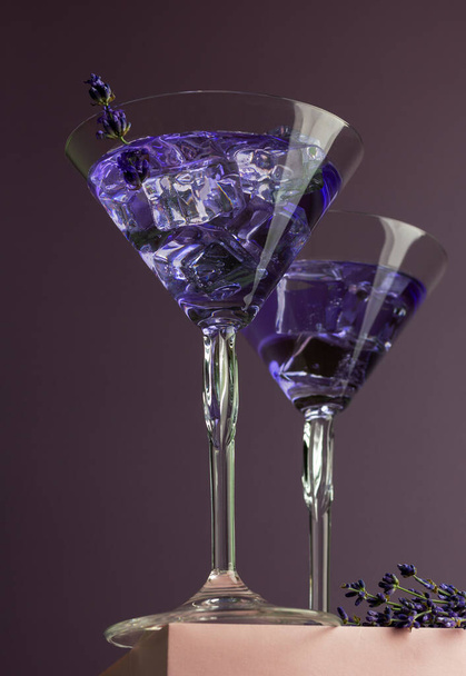 Drink met lavendelkruidenbloemen. Koude zomerse limonade of cocktail. Creatieve compositie met twee martini 's. Kopieerruimte. - Foto, afbeelding