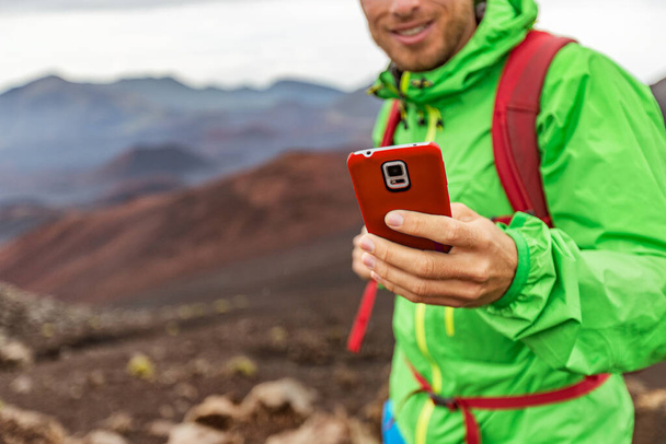 Phone man texting during trek hike in volcano mountain. Young person on travel lifestyle using his smartphone online. - Foto, Imagen