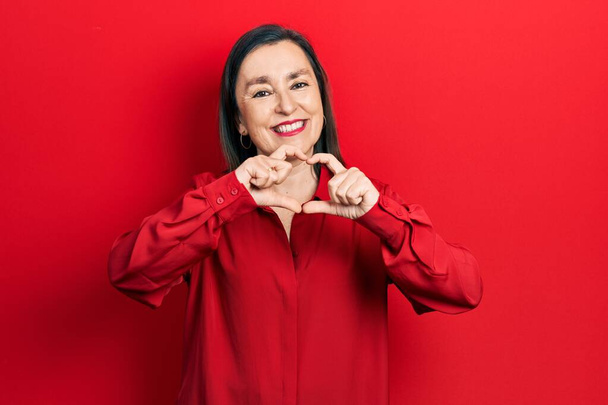 Middle age hispanic woman wearing casual clothes smiling in love doing heart symbol shape with hands. romantic concept.  - Photo, Image