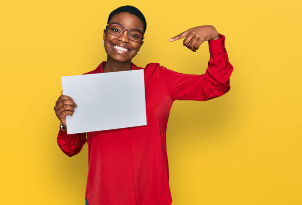 Giovane donna afroamericana con uno striscione vuoto che punta il dito verso un sé sorridente felice e orgoglioso  - Foto, immagini