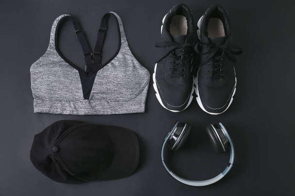 Sport shoes, top, cap and headphones on dark background - Photo, Image
