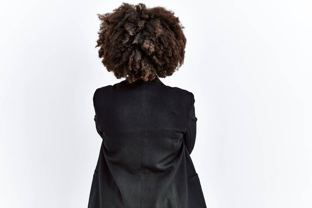Afroamerykanka z afro włosy ubrana w służbową kurtkę i okulary stojące tyłem patrząc z skrzyżowanymi ramionami  - Zdjęcie, obraz
