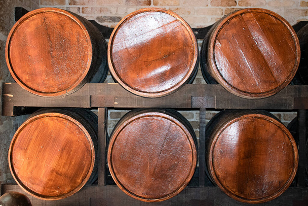 Hat fából készült alkoholos hordó egy polcon egy szobában. Ezek a szüret konténerek tárolhatnak bort, rumot, sört, whiskyt, brandyt, tequilát és más alkoholtartalmú italokat.. - Fotó, kép