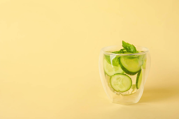 Glass with cucumber lemonade on color background - Фото, изображение