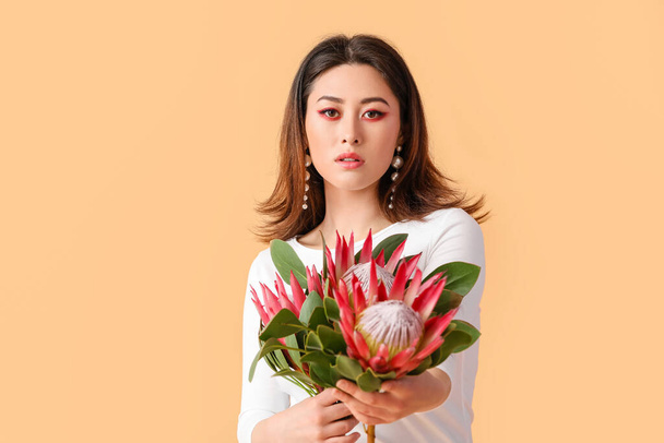 Beautiful young woman with protea flowers on color background - Photo, Image