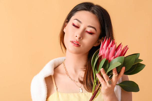 Beautiful young woman with protea flower on color background - Photo, Image
