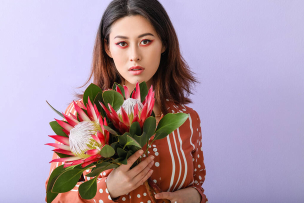 Bella giovane donna con fiori di protea su sfondo di colore - Foto, immagini