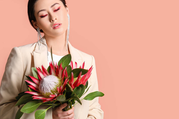 Beautiful young woman with protea flowers on color background - Fotó, kép