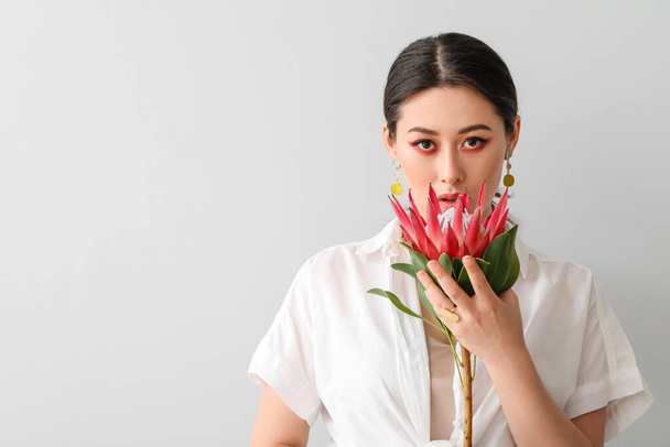 Bella giovane donna con fiore di protea su sfondo chiaro - Foto, immagini