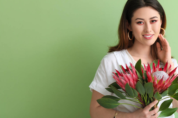 Beautiful young woman with protea flowers on color background - Foto, imagen