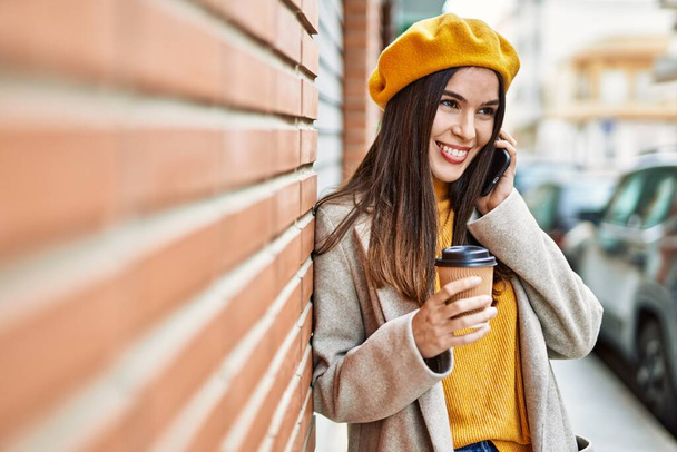 Młoda latynoska dziewczyna rozmawia przez smartfona pijąc kawę w mieście. - Zdjęcie, obraz