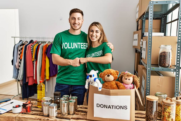 Giovane coppia di volontari ispanici sorridente pugni urto felice al centro di carità. - Foto, immagini