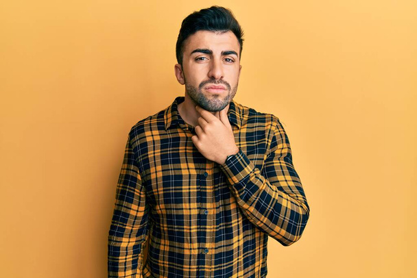Jonge Latijns-Amerikaanse man draagt casual kleding aanraken pijnlijke nek, keelpijn voor griep, clod en infectie  - Foto, afbeelding