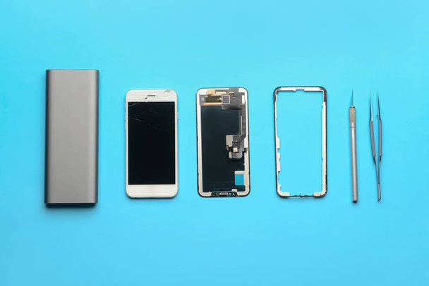 Téléphone portable démonté avec des outils de technicien sur fond couleur - Photo, image