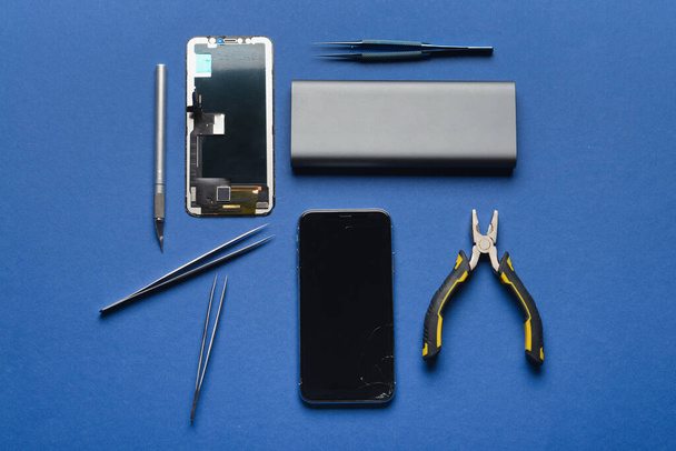 Disassembled mobile phone with technician tools on color background - Foto, Imagem