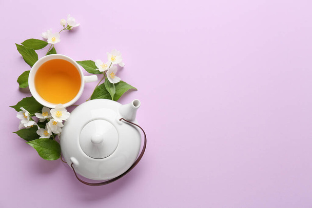 Složení s šálkem jasmínového čaje, konvice a květiny na barevném pozadí - Fotografie, Obrázek