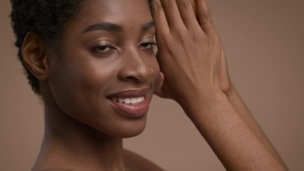 Vonzó fekete nő pózol megható arc és nyak, bézs háttér - Felvétel, videó