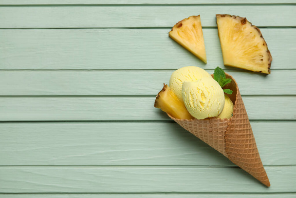 Вафельный конус с вкусным ананасовым мороженым на фоне цвета дерева - Фото, изображение