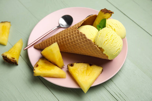 Talíř s chutnou ananasovou zmrzlinou v oplatce kužel na barevném dřevěném pozadí, detailní up - Fotografie, Obrázek