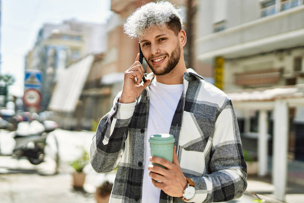 Giovane uomo ispanico parlando smartphone bere caffè in città. - Foto, immagini