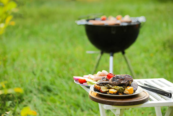 Table with tasty steak and vegetables outdoors - Photo, Image