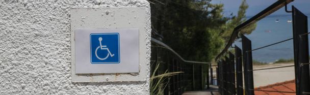 壁に青い四角形の障害者用車椅子アクセスシンボル - 写真・画像