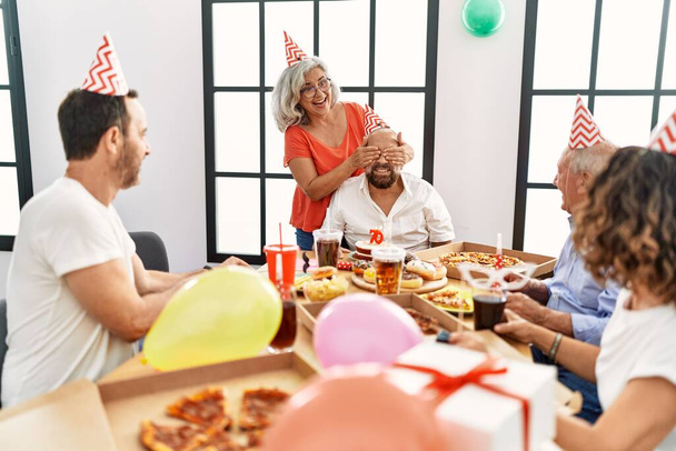Grupo de amigos de mediana edad sonriendo feliz celebrar cumpleaños en casa. - Foto, imagen