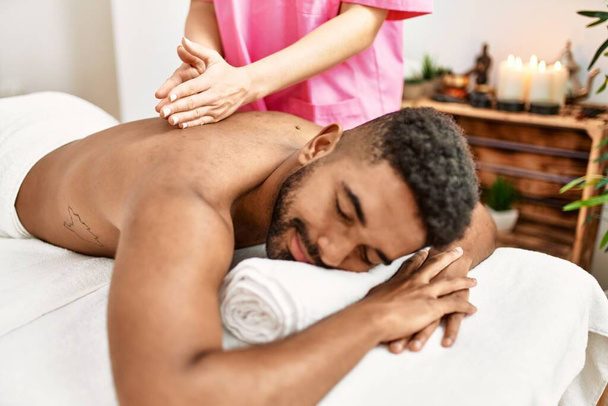 jong afrikaans amerikaans glimlachen gelukkig reciving terug massage bij beauty center. - Foto, afbeelding