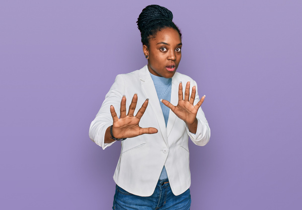 Jonge Afro-Amerikaanse vrouw draagt zakelijke kleren bang en doodsbang van angst uitdrukking te stoppen met gebaar met de handen, schreeuwen in shock. paniekconcept.  - Foto, afbeelding