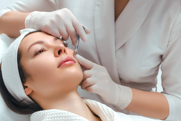 Lipvergroting en correctie procedure in een kosmetologische salon. De specialist injecteert de lippen van de patiënt. - Foto, afbeelding